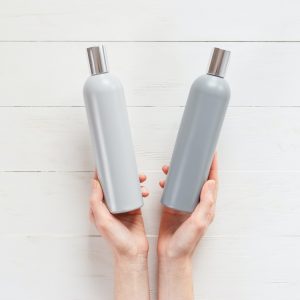 The woman chooses one of the two shampoos in the bottle