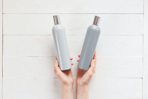 The woman chooses one of the two shampoos in the bottle